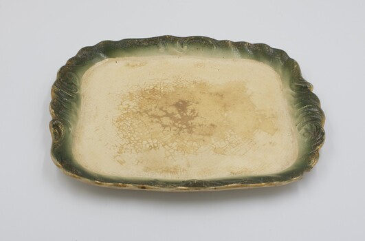 Cream colored plate with decorative green edging with gold rim.