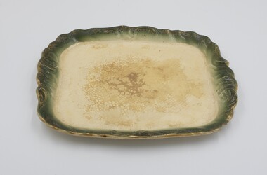 Cream colored plate with decorative green edging with gold rim.