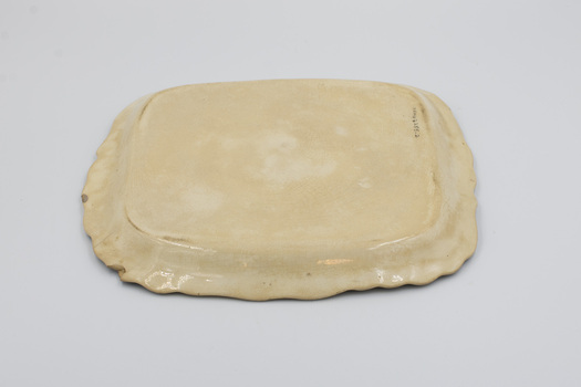 Upside down view of rectangular cream-colored ceramic plate with decorative edging.