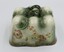 Long side of rectangular ceramic cheese plate with floral design on side and handle on top.