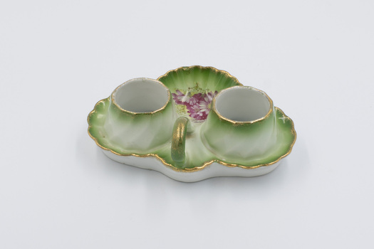 Back of ceramic cruet set with carry handle in foreground and salt cellar and pepper dispenser removed.