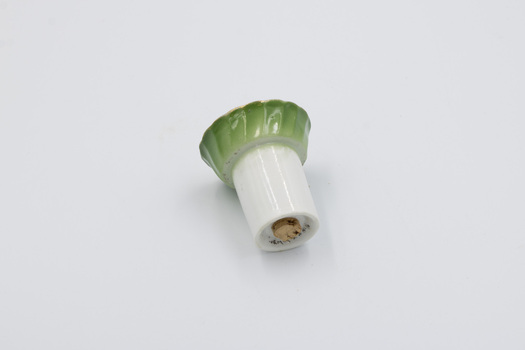 Ceramic pepper dispenser lying on side with bottom and cork stopper visible.