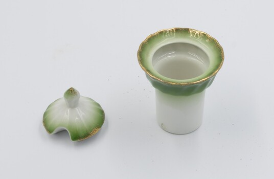 Salt cellar with lid removed and placed next to it. Both have green decorative rim on white background with gold rim around salt cellar.