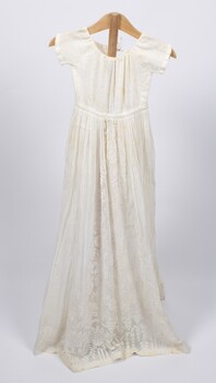 Front view of long cream-colored christening gown on a stand