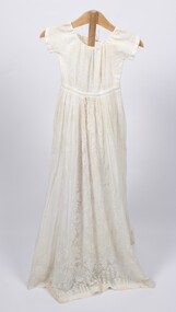 Front view of long cream-colored christening gown on a stand