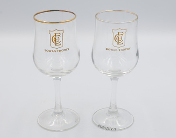 Two gold-rimmed wine glasses with ECC logo and Bowls Trophy wording on the front of each glass.