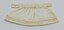 Doll's apron laid flat with decorative stitching visible.