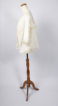 Side view of cream-colored ladies jacket on mannequin with one lace-trimmed sleeve visible