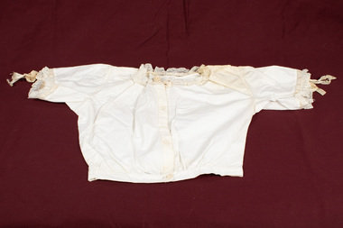 Lace-trimmed cream-colored child's blouse laid flat.