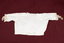 Child's blouse laid flat. Cream-colored with lace trim at sleeves and neck.