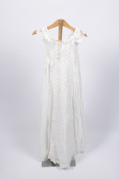 Front view of christening gown hung from wooden hanger