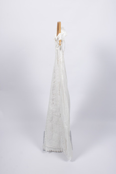 Side view of christening gown hung from wooden hanger