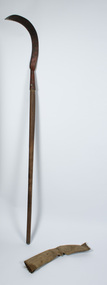 Scythe with blade upright and blade cover on the ground beside the handle