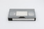 VHS tape in casette inside clear plastic container with label visible.
