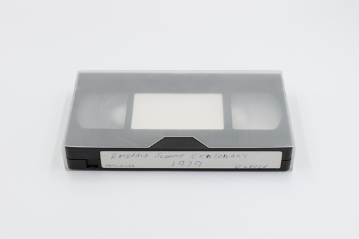 VHS tape in casette inside clear plastic container with label visible.