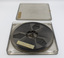 Clear plastic case with lid open showing film inside and label.