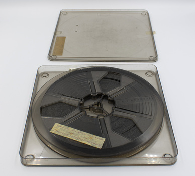 Clear plastic case with lid open showing film inside and label.