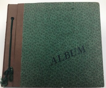 Front cover of postcard album. Embossed green. Brown leather binding with green cord.