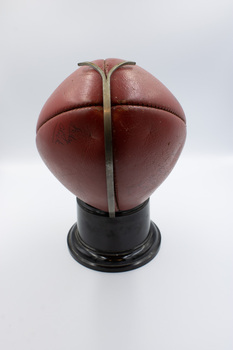 Back view of football showing a metal clasp securing it to the stand