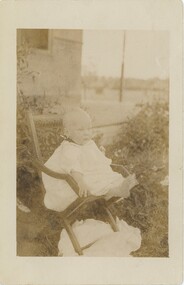 Black and white photo of Jack Nobelius at 12 months old, sitting in a garden printed on to card.