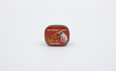 The front of a metal container, with decorations featuring a red background, a dog, and a gramophone.