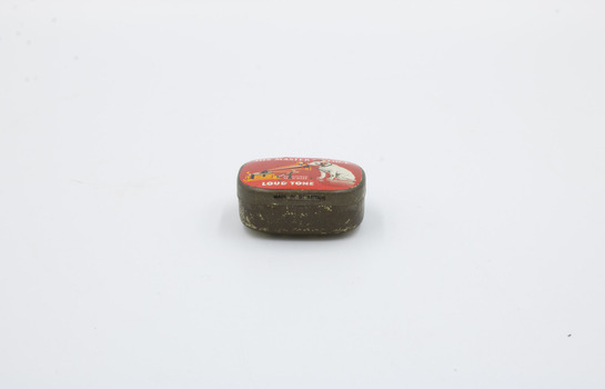 A metal container with red decoration on top, focused on the point where the tin opens.