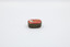 A metal container with red decoration on top, focused on the hinge on the side.