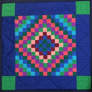 Front of patchwork quilt - design is mainly in blue and green colors with some pink and burgundy.