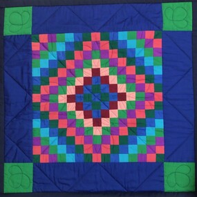 Front of patchwork quilt - design is mainly in blue and green colors with some pink and burgundy.