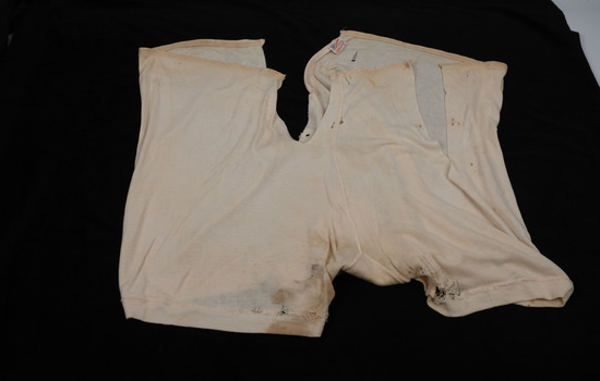 An aged set of white women's underwear, with stains and tears in the fabric.