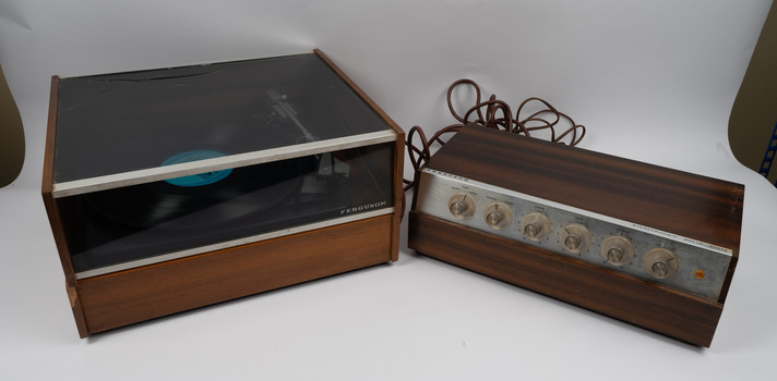 Front view of turntable with record inside the turntable and amplifier beside it.