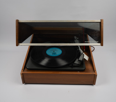 Front of turntable opened to show record and tonearm holding cartridge and stylus.