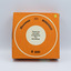 Top view of orange box containing rotary slide magazine with information in English in the centre of box and small price sticker in top right.