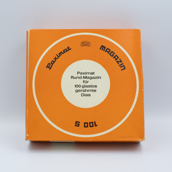 Bottom view of orange box containing rotary slide magazine with information in German in the centre.