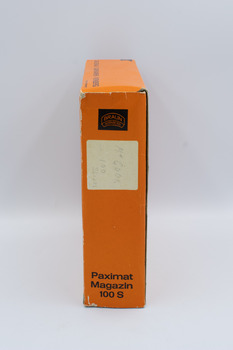 Side view of orange box containing rotary slide magazine with brand name visible and hand-printed label of contents.