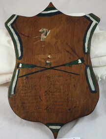 Front of wooden shield showing names of team members hand-written.