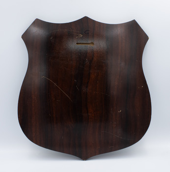 The wooden reverse of a shiled-shaped trophy plaque.