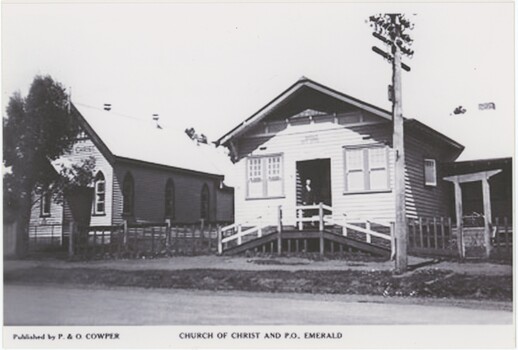 A black and white photograph featuring two buildings by a road, with publication and photograph details printed below.