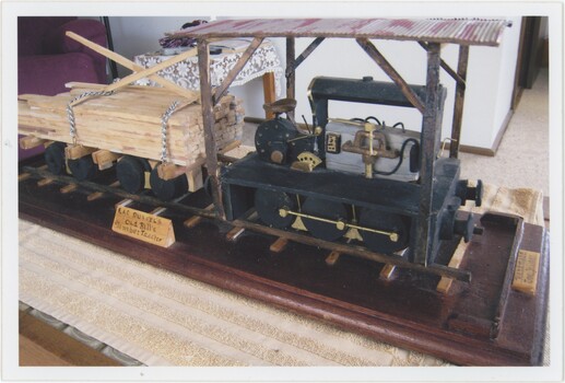 The obverse of a colour photograph picturing a model of an old rail tractor.