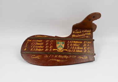 Front of rudder showing individual names of the winning rowing team inscribed in gold lettering.