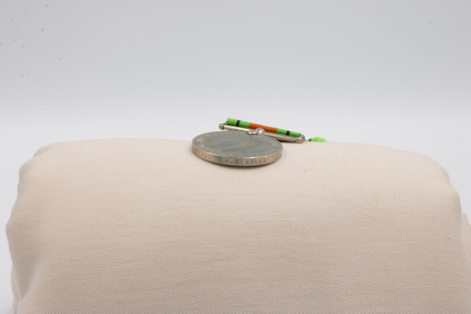 The edge of b, the Defence Medal, revealing text.