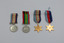 The reverses (tail or rear side) of the four medals detailed in this entry, arranged left-to-right a, b, c, d.