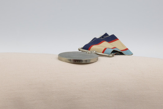 The edge of a, the older Australia Service medal, showing inscribed text.