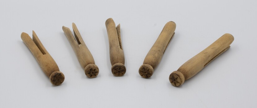 Five wooden clothes pegs lying flat with their heads in foreground