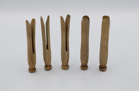 Five wooden clothes pegs positioned upright on their heads