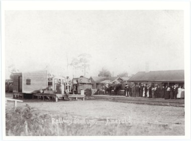 A black and white photograph of a train station crowded with people with a written caption at the bottom.
