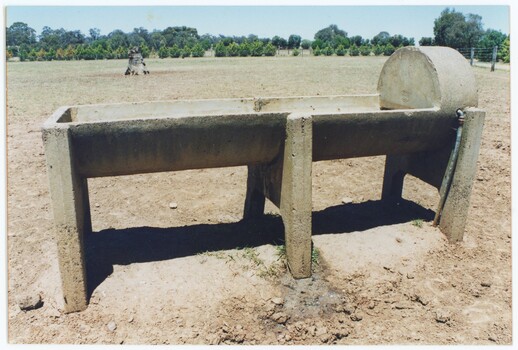 A printed colour photograph depicting a concrete trough from side-on, with a pipe going into the higher right side.