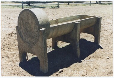 A colour photograph of a concrete trough, viewed from an angle with a raised section in the foreground.