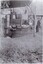 A black and white photograph of a eucalyptus distillery, with two women sitting on a storage tank and a man standing beside them.