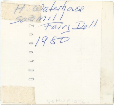 The reverse of a photograph, with handwriting in blue pen and a printed serial number.